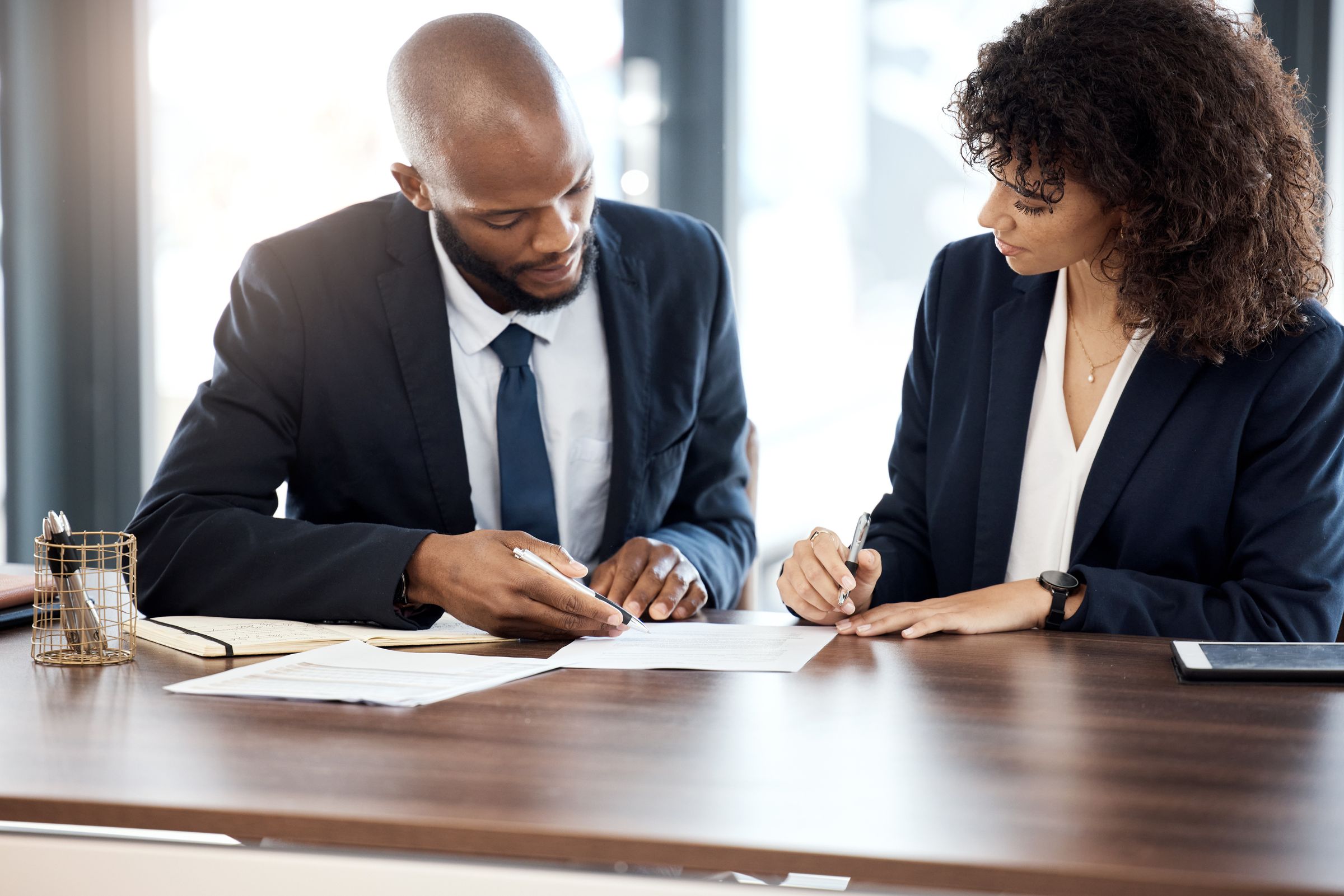 Two lawyers signing documents together at a meeting table
