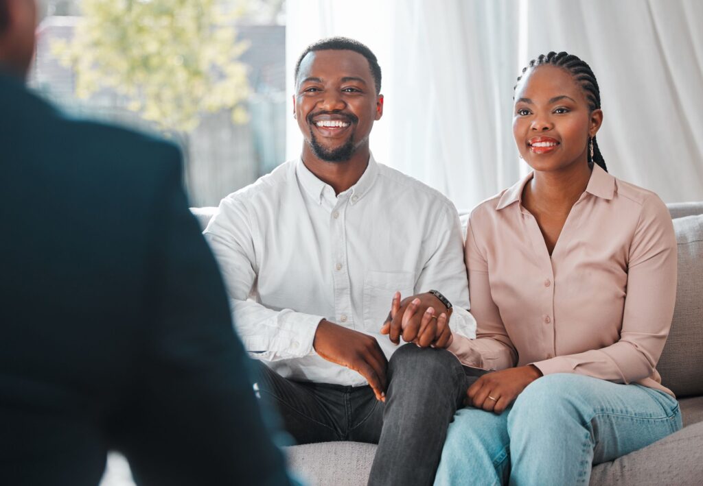 A smiling couple on a sofa during a consultation