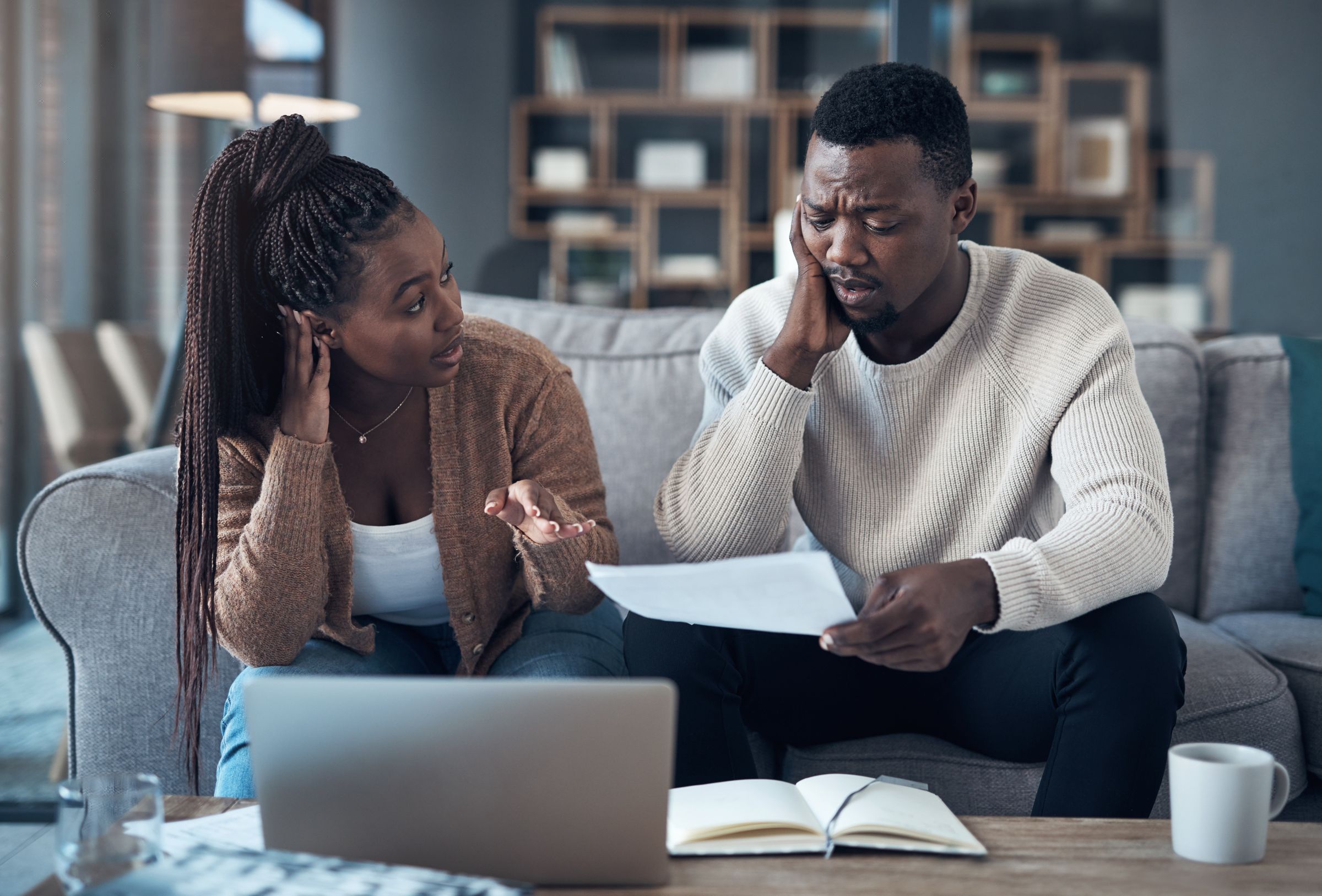 A worried couple going through home loan paperwork in their lounge