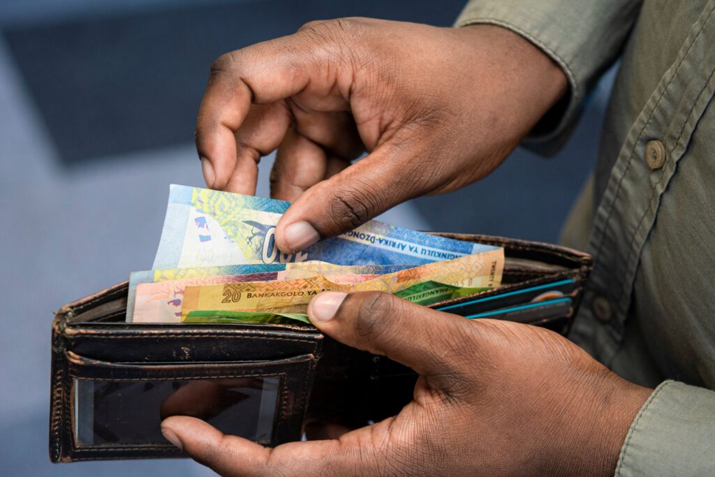 A man taking South African rand banknotes out of a leather wallet