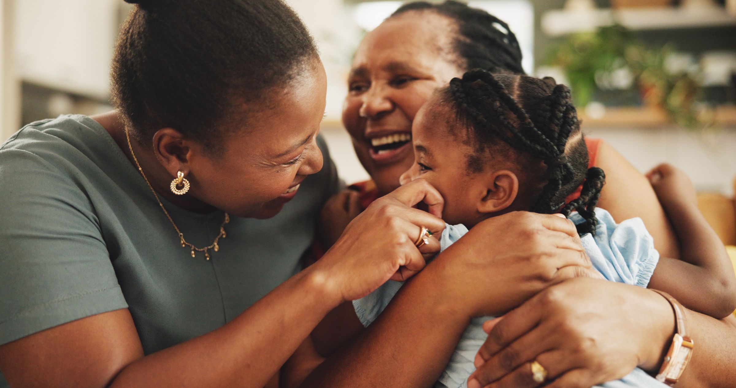 A grandmother, mother and daughter embracing at home