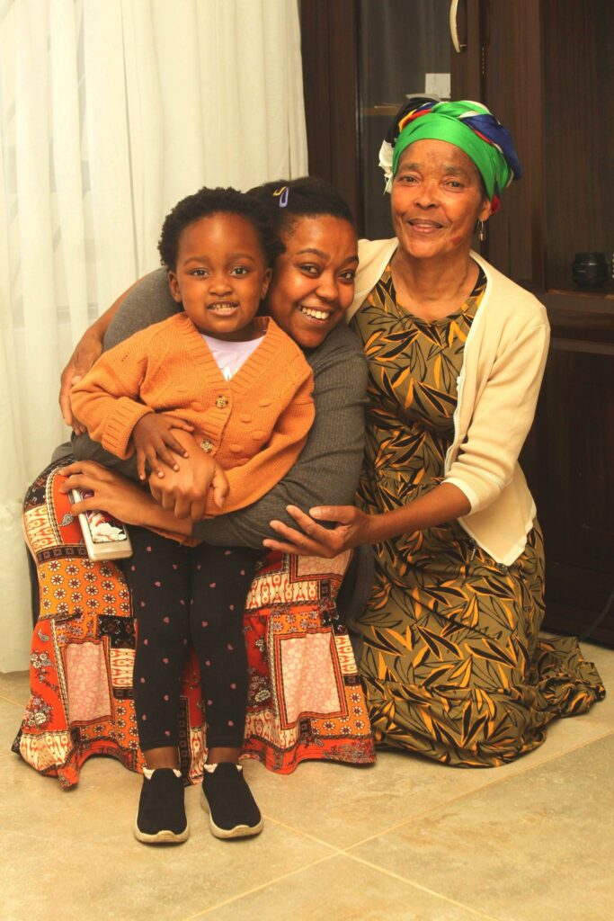 A grandmother, mother and toddler embracing at home in Johannesburg