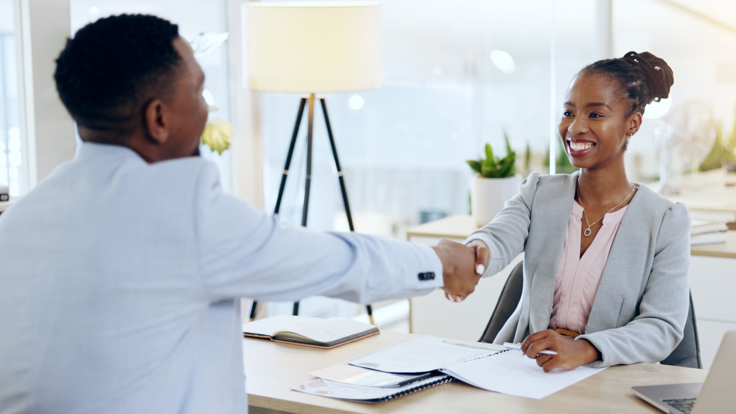 An employer and an employee shaking hands across a desk