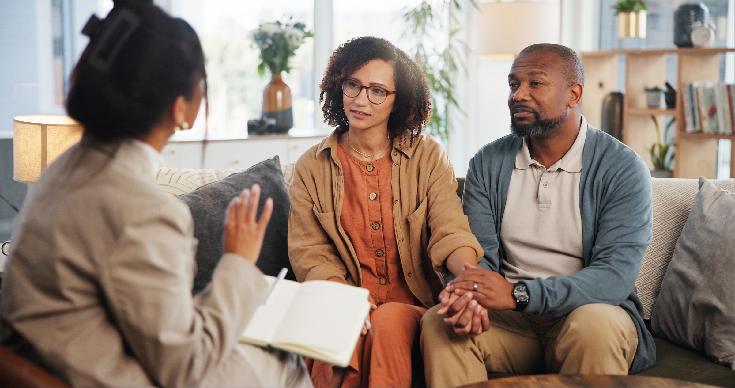 A couple holding hands while they speak with a mediator